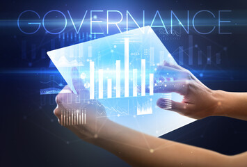 Hand holding futuristic tablet with GOVERNANCE inscription above, modern business concept