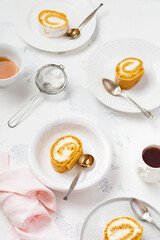 Dessert pumpkin roll with butter cream and orange server for the festive table on light gray background. Selective focus.
