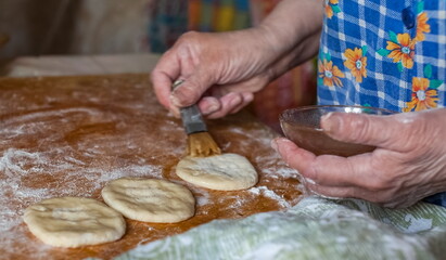 Dough discs and women's hands lubricating melted butter discs, wheat flour on a wooden cutting Board closeup