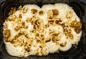 Milk rice porridge with sliced walnuts close-up on a black plastic substrate
