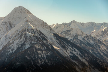 melting snow reveals texture of mountin with trees begining to show after winter