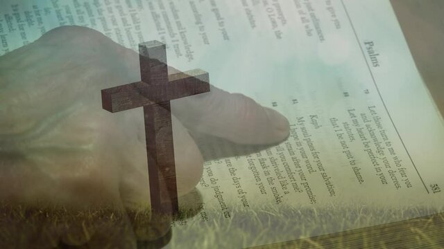 Animation of christian cross and person with finger on holy bible