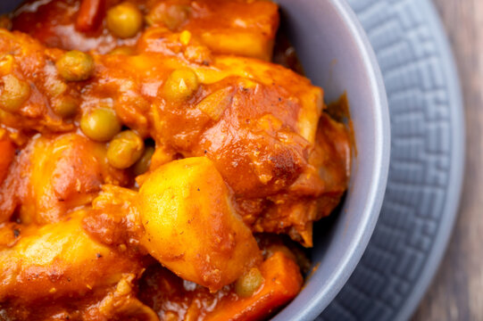 Chicken Afritada  (Spanish-style Chicken Stew)  (Close Up)- is a well-known Filipino dish that is cooked in tomato sauce with carrots, potatoes, green peas and bell peppers as the main vegetables.