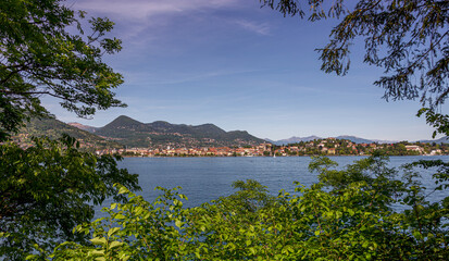 Looking through trees across a lake to a pretty Italian town