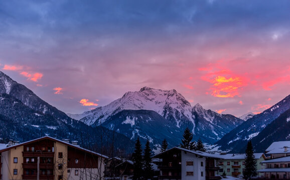 Unfocused ski lodge below a stunning sunset with snowcapped mountains
