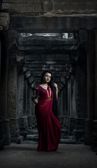 Beautiful indian girl dancer in the posture of Indian dance . Indian classical dance bharatanatyam. Girl wearing traditional Indian red saree, gold jewellery and bangles.Maa Durga shoot concept