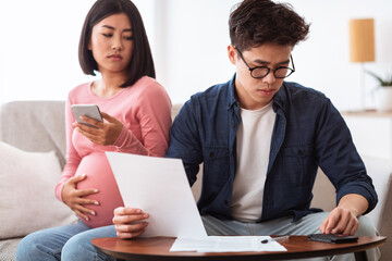 Concerned Asian Couple Calculating Expenses Looking At Bills At Home