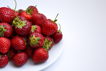 Strawberries on white plate. Freshly picked strawberry. Organic berries on white background. Village garden harvest.