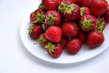 Strawberries on white plate. Freshly picked strawberry. Organic berries on white background. Village garden harvest.