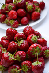 Strawberries on white plate. Freshly picked strawberry. Organic berries on white background. Village garden harvest.