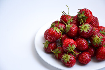 Strawberries on white plate. Freshly picked strawberry. Organic berries on white background. Village garden harvest.
