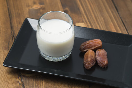 milk and dates in the black plate on a wooden table