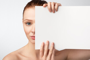 Red-Haired Woman Holding Poster Covering Half Of Face, White Background