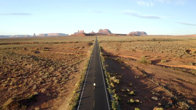 Aerial Drone footage of man walking in monument valley, along empty forest Gump highway in Utah