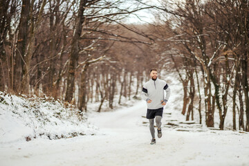 Sportsman jogging in nature on snow at winter. Healthy lifestyle, winter fitness, cold weather