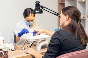 Manicurist doing a manicure in a nail salon using a nail file