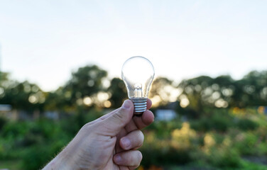Light bulb in hand at sunset. The concept of renewable energy, electricity
