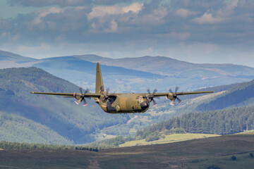 RAF (Royal Air Force) Green camouflage Lockheed C-130 Hercules transport flying low level in the...