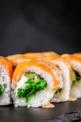 appetizing sushi roll philadelphia with salmon cucumber and chuka on a black stone plate