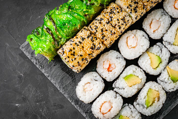 appetizing set of sushi roll on a black stone plate