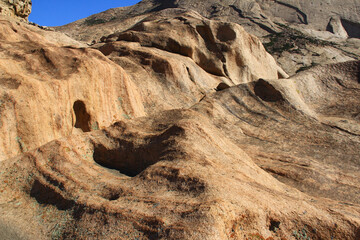 Smooth slope of Bektau-Ata volcanic mountains close-up in summer. Volcanic smooth yellow-brown mountains close, undulating slopes with depressions and furrows, summer, sunny