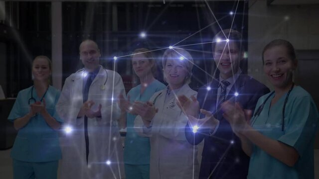 Network of connections against team of medical professional clapping at hospital