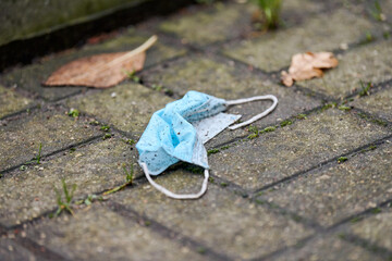 Used medical mask on street ground