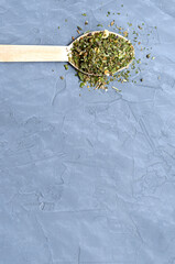 Dried herbs and spices in a wooden spoon on a gray concrete background. Provencal herbs, basil,...