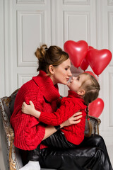 mom and daughter sit in a chair and kiss on a white background