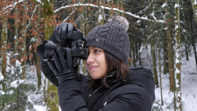 Asian camera girl taking pictures in the snowy woods in Switzerland