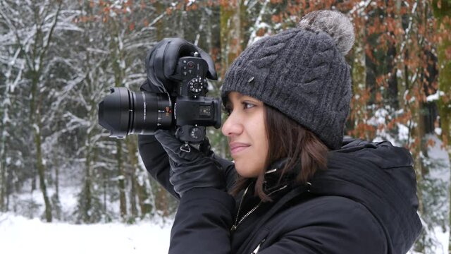 Young woman taking photos with a professional camera in winter woods.