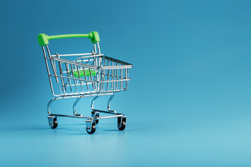 An empty supermarket cart on a blue background.