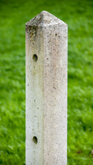 Poste de hormigón en prado de hierba verde