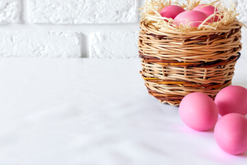 Easter composition with wicker basket and pink colored eggs