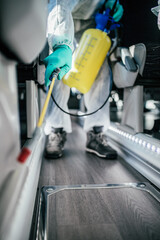 Professional chemical cleaning bus seats. Bus disinfection. Exterminator in workwear.