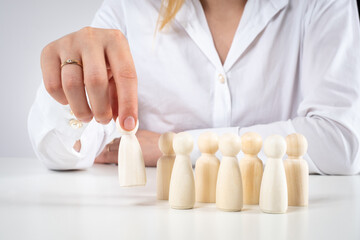 Recruitment of personnel. A woman chooses one human figure from several. The HR Manager selects employees for the vacancy. Choosing the most suitable employee.