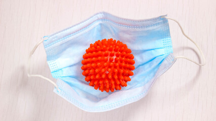 A medical protective mask containing a red ball with spikes that looks like a coronavirus molecule.