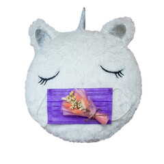 on a white cute pillow lies a purple medical mask, and on top is a small bouquet of dried flowers on a white background