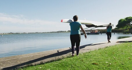 Two senior caucasian women carrying a rowing boat - Powered by Adobe