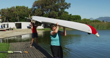 Senior caucasian man and woman carrying a rowing boat - Powered by Adobe