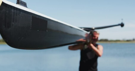 Senior caucasian man carrying a rowing boat - Powered by Adobe