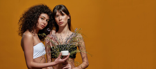 Female holding a cream in a jar before the bouquet