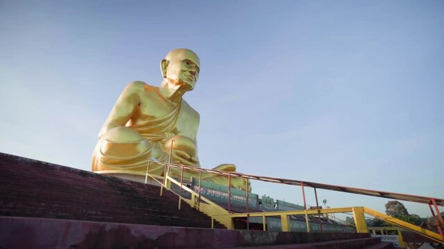 4k Upstairs to a golden statue of a buddhist monk Luang Pu Thuat. Big Golden Statue in mountains at beautiful sunrise in Khao Yai, Korat province.