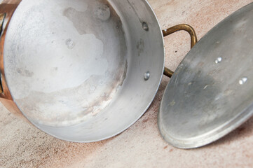 Old copper casserole on a concrete background.