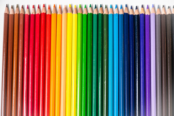 Some different colored wooden pencil crayons placed in a row in front of a white isolated background