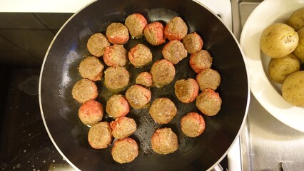 Homemade meatballs are slowly cooking in the pan
