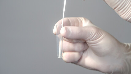 
A nurse wearing latex gloves holds the tube with serum and inserts and removes the swab with the patient's sample to obtain the Covid-19 result.