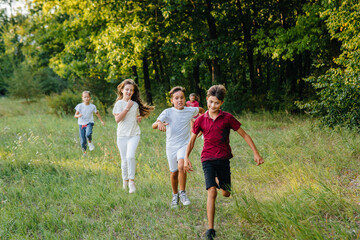 Fototapeta premium A group of happy children run and play in the Park during sunset. Summer children's camp