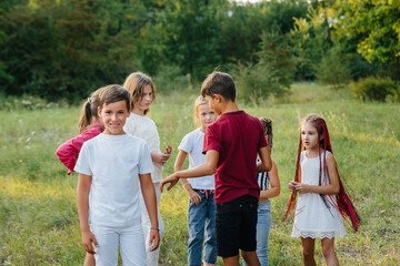 Naklejka na ściany i meble A group of happy children run and play in the Park during sunset. Summer children's camp