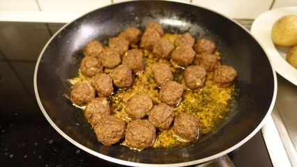 Homemade meatballs are slowly cooking in the pan